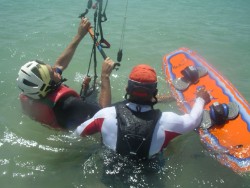 En la escuela de kitesurf Tarifa Max, nuestra compromiso: tu monitor en el agua contigo para ayudarte en ponerte la tabla de kitesurf